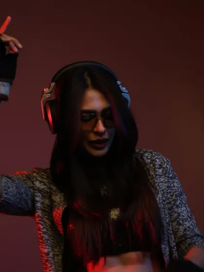 A moody studio shot where I'm lost in the music with my headphones on. The red and blue lighting creates a cool, atmospheric vibe that reflects my deep house and electronic sets.