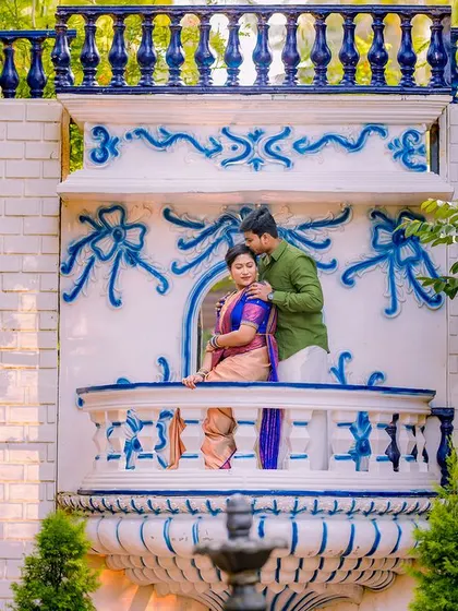 A romantic "Romeo and Juliet" moment on a balcony. The groom's tender kiss on the bride's forehead is a timeless gesture of love, beautifully captured in their ethnic wear.