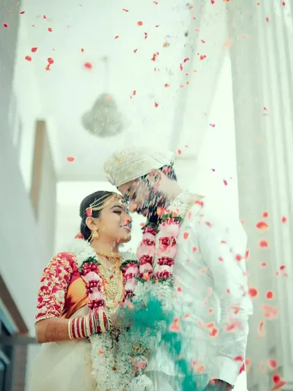 A dreamy and romantic portrait of a couple during their wedding ceremony, with flower petals showering down around them.