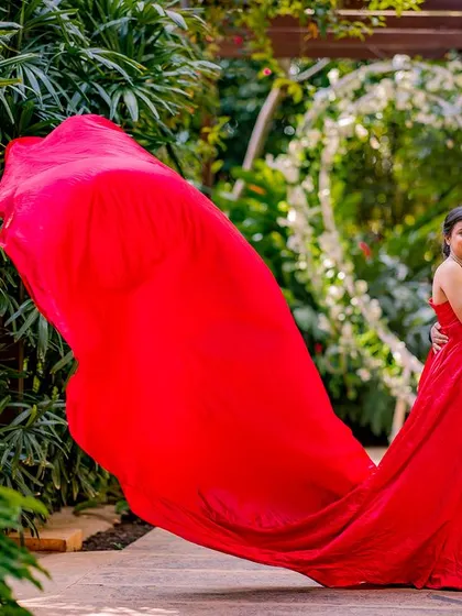 A romantic pose in front of the heart-shaped floral arch. The flowing red gown is caught in motion, adding a dynamic and passionate feel to this lovely pre-wedding photo.