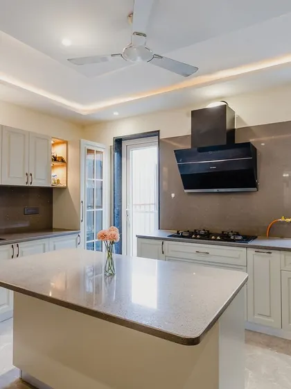 The kitchen is filled with natural light from the window and door, making it a pleasant space to cook in. The classic cabinet design adds timeless appeal.