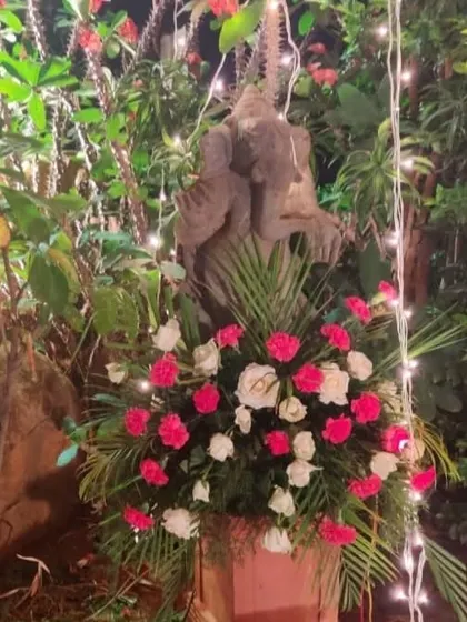 A simple yet beautiful detail. A floral arrangement of pink and white roses sits at the base of a Ganesha statue, blending spiritual elements with natural beauty.