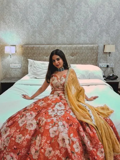 A seated portrait in the floral lehenga, showing its voluminous skirt.