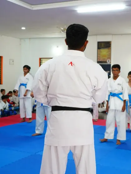 A black belt instructor referees a sparring session, ensuring safety and fair play among the students.