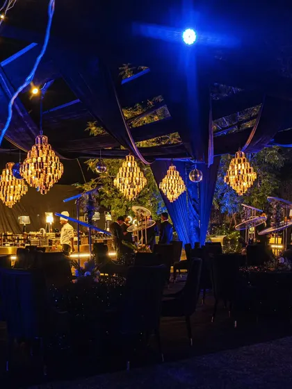 The moody and sophisticated ambiance of a Diwali party, with dark drapery, dramatic blue lighting, and sparkling chandeliers.