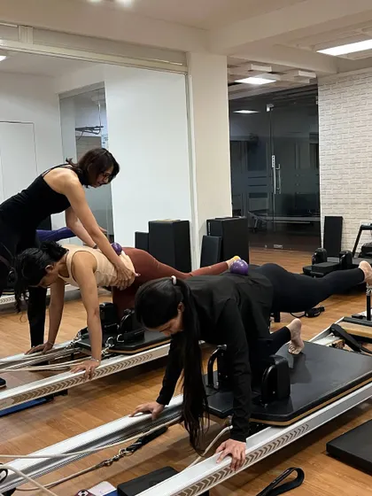 Trainees practice hands-on adjustments and teaching techniques during a reformer session, a crucial part of our certification program.