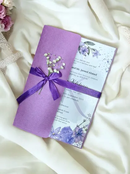 A personalized lavender wedding invitation with watercolor florals, a satin ribbon, and a touch of dried baby's breath for a romantic finish.
