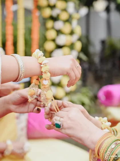 A detail shot of the beautiful floral bracelets being tied on the bride's wrist during the Haldi ceremony.