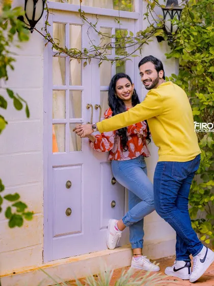 A fun, dancing pose in front of a white door. The couple's casual outfits and their joyful interaction make this a very sweet and candid shot.