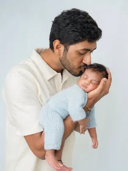 A father gently kisses the forehead of his sleeping baby.