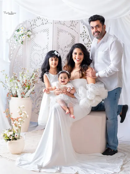 A happy family of four dressed in white. This full portrait captures the joy of the parents with their two lovely daughters.