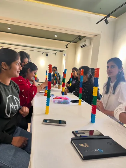 A group of teachers fully engaged in a building challenge during the Six Bricks workshop. This hands-on practice is crucial for understanding how to guide similar activities in their own classrooms.