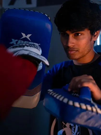 A student holding pads for his training partner, showing intense focus. Holding pads is a skill in itself, and it's a key part of how we train together as a team.
