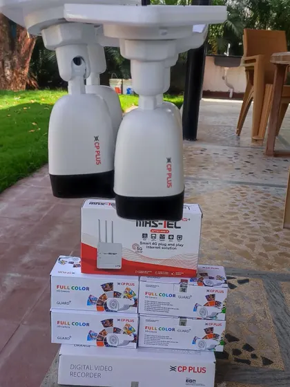 A pair of CP Plus pan-tilt-zoom cameras alongside the full-color camera boxes and 4G router, showcasing a powerful setup for a large area.