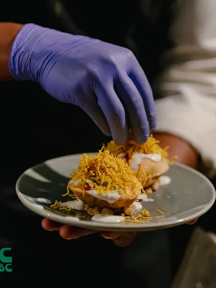 Our chef adding the final touches to a plate of dahi puri. This popular Indian street food snack is a burst of tangy and savory flavors.