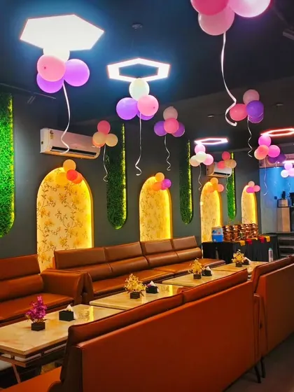 A simple yet effective decoration for a cafe party. Bunches of pink and purple balloons are hung from the ceiling, adding a festive touch to the entire space.
