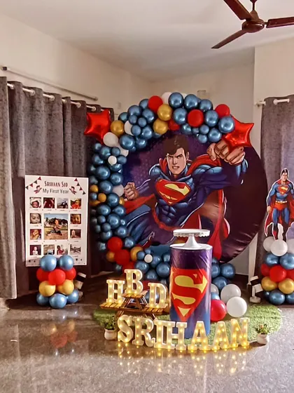 It's a bird, it's a plane, it's Superman! We designed this superhero theme for Srihaan's first birthday, featuring a bold backdrop with the Man of Steel, a red, blue, and yellow balloon garland, and a "My First Year" milestone board.