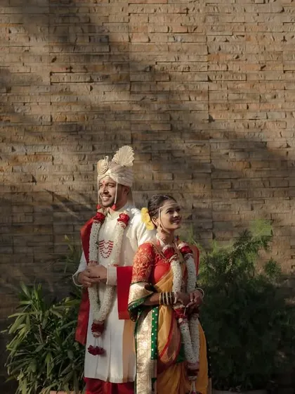 A beautifully composed shot of a Maharashtrian couple standing against a textured wall, with artistic shadows creating a dramatic and timeless feel.