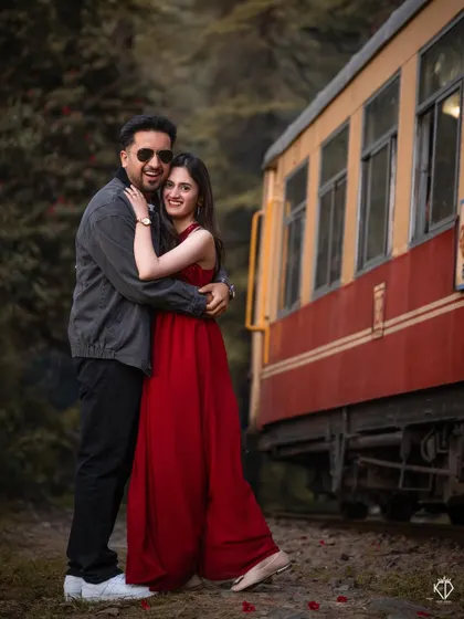 A happy, candid embrace next to the classic red carriage of the Kalka-Shimla Rail. This shot captures the joy and excitement of a destination pre-wedding shoot.