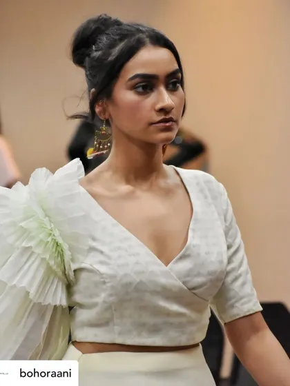 A backstage moment with a model wearing our signature ruffled sleeve blouse. This close-up highlights the texture of the fabric and the unique silhouette of the sleeve.
