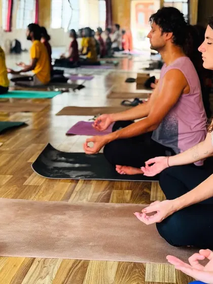 Two students sit side-by-side in meditation, embodying the focus and serenity we cultivate in our classes. The practice of sitting in stillness is as important as the physical postures.
