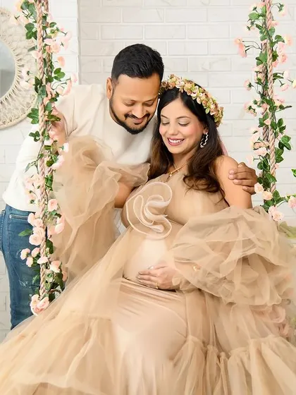 A tender moment between the expecting couple on our floral swing. The soft, natural light and the beige ruffled gown create a warm and romantic atmosphere.
