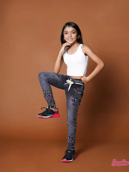 A confident and cheerful pose for a kids' apparel brand. The simple background keeps the focus entirely on the model and the clothing.