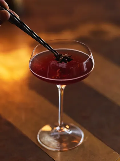The final touch. A star anise is carefully placed on our Pickled Pom Whiskey, adding an aromatic finish to this bold and tangy cocktail.