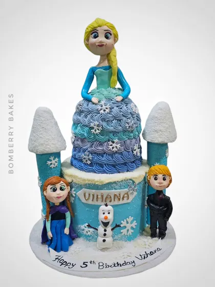 A 3kg Belgium chocolate truffle cake with a Frozen theme, featuring a sculpted Elsa doll, castle turrets, and figurines of Anna, Kristoff, and Olaf.