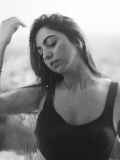 A black and white portrait through a wet window, creating a soft, blurry, and emotional effect.