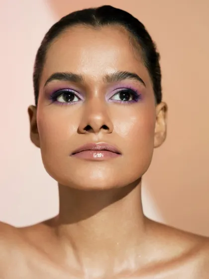 A close-up of the purple eye look, where you can see the incredible highlight on the cheekbones and the smooth, radiant finish of the skin.