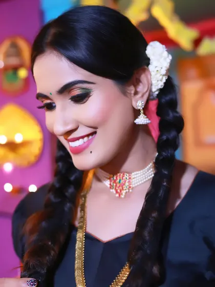A smiling close-up portrait of a model in a traditional look, with her hair in braids and adorned with classic jewelry.