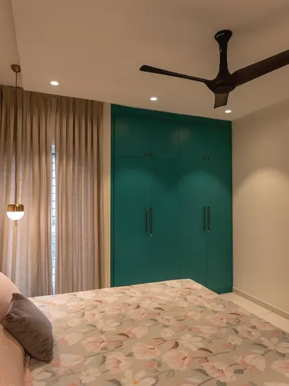 Another angle of the turquoise-themed bedroom, showing the interplay of natural light from the window with the warm interior lighting. The floral bedding adds a soft, delicate touch.