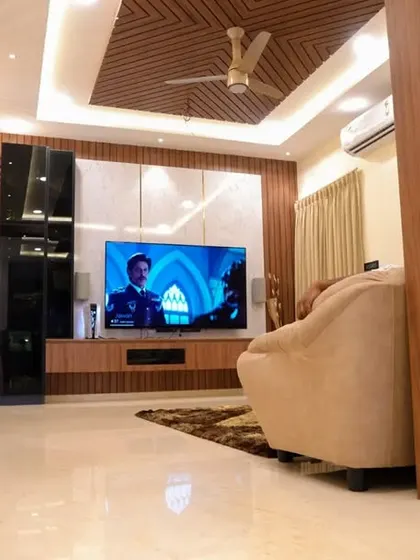 A view of the TV unit in the Velachery apartment, with a wooden rafter ceiling and a combination of open and closed storage.