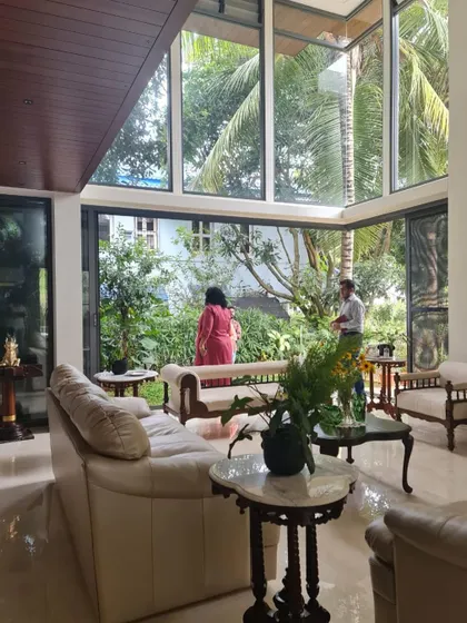 The double-height living room of "Casa Magnifera" is wrapped in glass, offering panoramic views of the garden and blurring the line between inside and out.