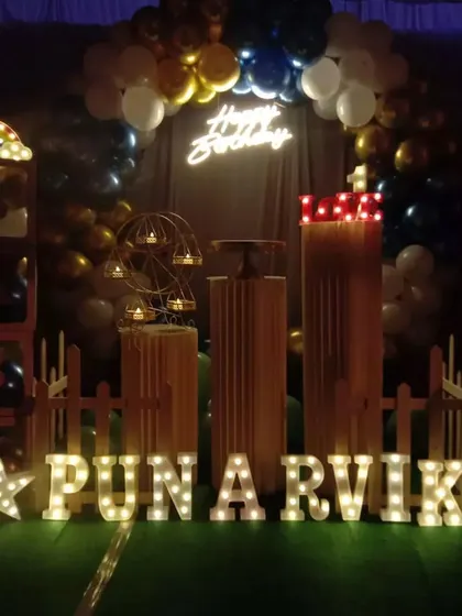 This first birthday setup for Punarvik included a white picket fence prop and "BABY" blocks for a playful touch. The gold, white, and black balloon arch and personalized marquee letters created a festive photo corner for the family.