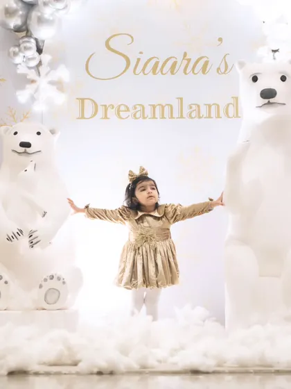 The birthday girl, Siaara, posing sweetly between two life-sized polar bear props in her magical winter dreamland.