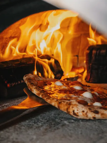 I'm always busy in the kitchen, prepping delicious pizzas to serve you the best. The fire is always burning, ready for your order.