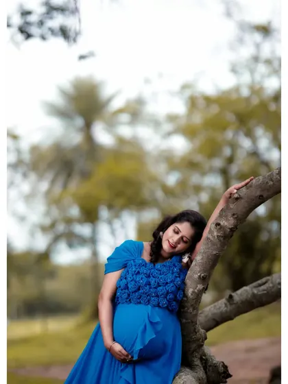 A serene portrait of a mom-to-be in the sky blue maternity gown. The 3D floral work on the bodice adds a beautiful textural detail to the dress.