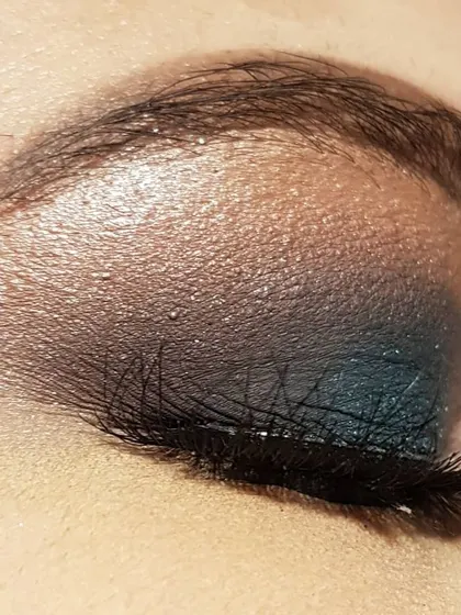 A side view of the teal smokey eye. This angle shows how the false lashes add volume and length, completing the dramatic eye makeup look.