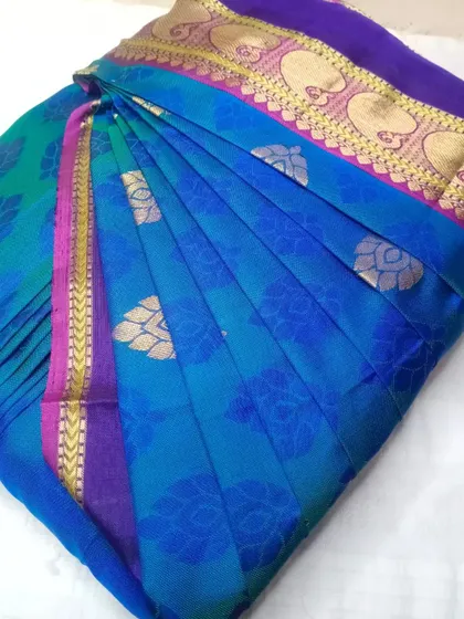 A stunning peacock blue saree with a contrasting purple border. It's been pleated and box folded, ready for the client.