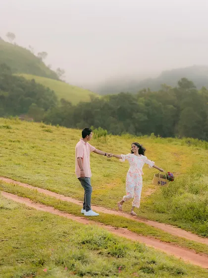 A playful, dancing moment on a hilltop path. The vast, misty landscape of the Western Ghats provides a stunning backdrop.