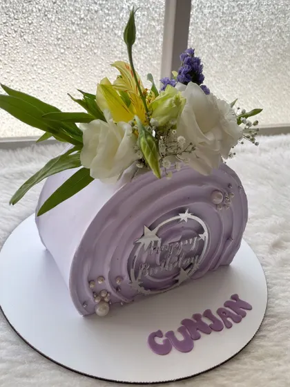 A top-forward cake in a lovely lilac shade, decorated with a fresh flower arrangement. This modern cake shape is perfect for a stylish birthday celebration.