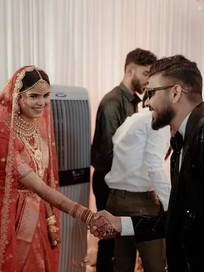 The first handshake as husband and wife. This candid shot captures the bride's joyful smile and the happy applause from family and friends.