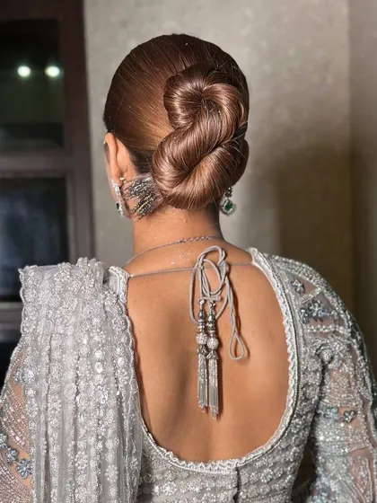 A bridal look isn't complete without the perfect hairstyle. This sleek, intricate bun is a timeless choice that is both elegant and secure, ensuring your hair looks flawless from the first photo to the last dance.