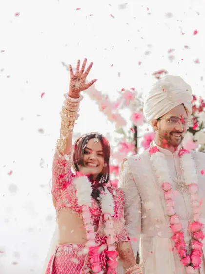 Just married! The couple waves to their guests, their faces beaming with happiness, as petals shower down on them at their beautiful beach wedding.