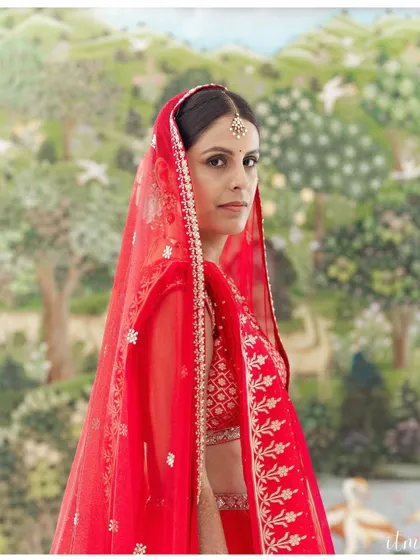 A stunning bridal portrait. The bride's direct gaze is powerful, and the vibrant red of her veil contrasts beautifully with the soft, artistic background. I aim to capture the strength and beauty of every bride on her special day.
