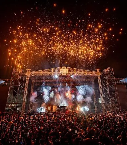 The full scale of the Sunburn Arena with Armin van Buuren, complete with a massive stage, a huge crowd, and a sky full of fireworks.