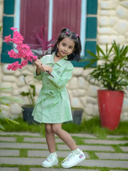 This little girl looks so stylish in her green dress, holding a pink flower. Our garden provides a beautiful natural backdrop for fashion-forward kid's photography.