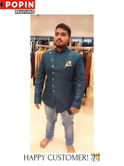 This happy customer is trying on a teal asymmetrical Indo-Western jacket. The unique cut and button placement make it a modern and stylish choice.